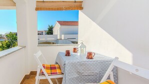 A balcony with a table and chairs, a view of buildings, and a clear sky. - Apartments Ladika (Vir)