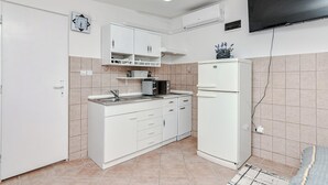 A compact kitchen with white cabinets, a microwave, and a refrigerator. - Apartments Ladika (Vir)