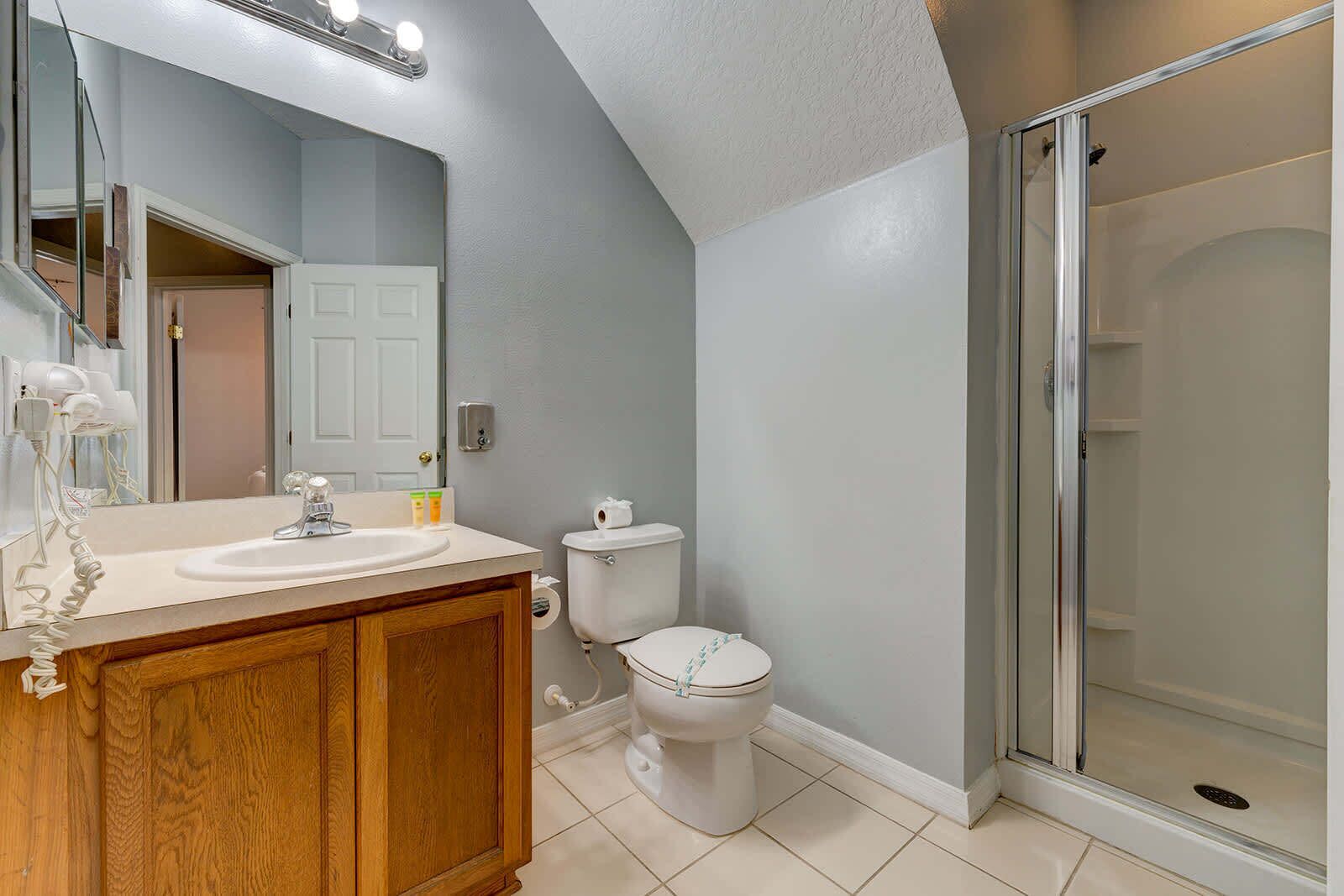 Une salle de bain avec un meuble-lavabo en bois, des toilettes et une cabine de douche en verre.