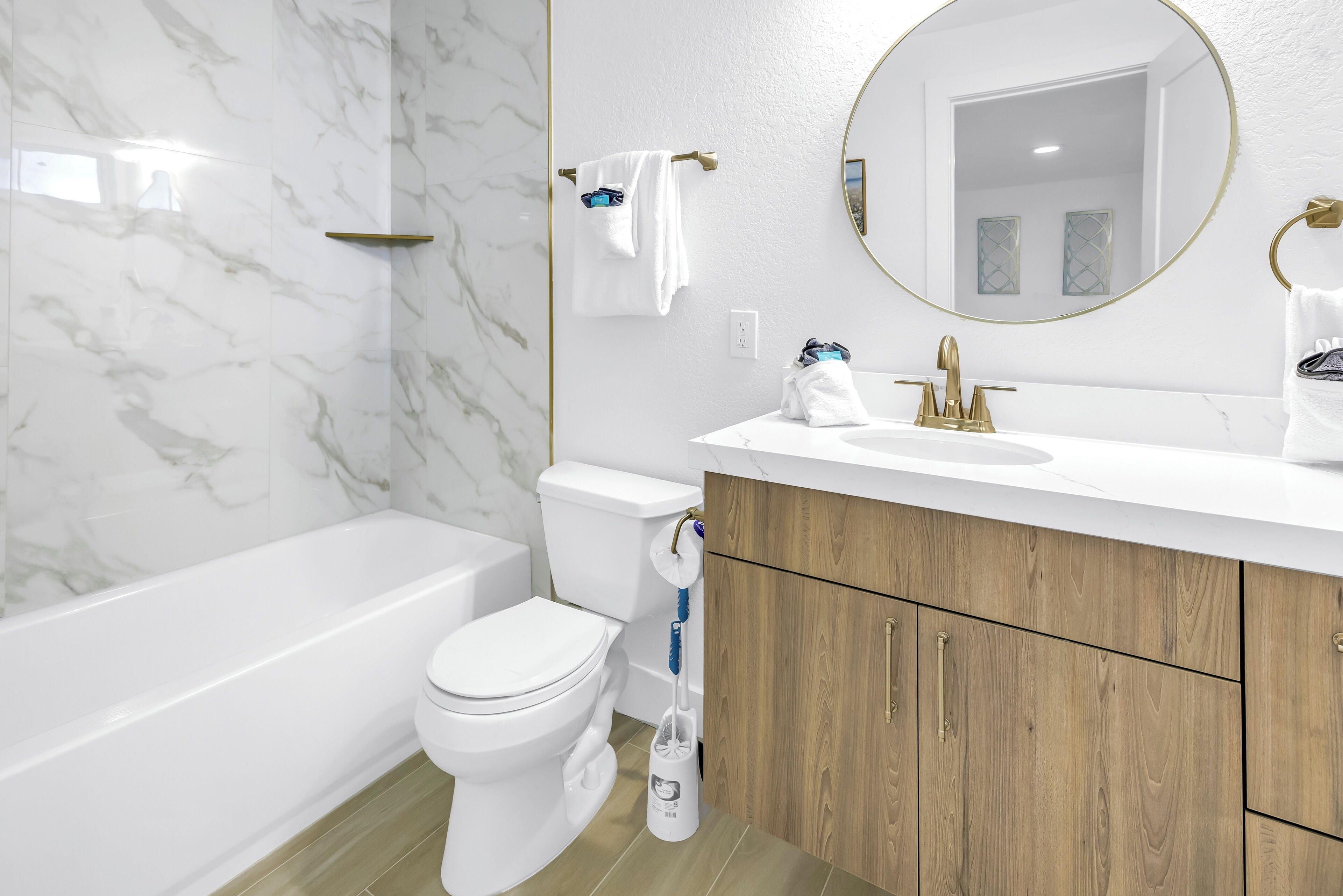 Une salle de bain moderne avec un mur en marbre, une baignoire, des toilettes et des meubles en bois.