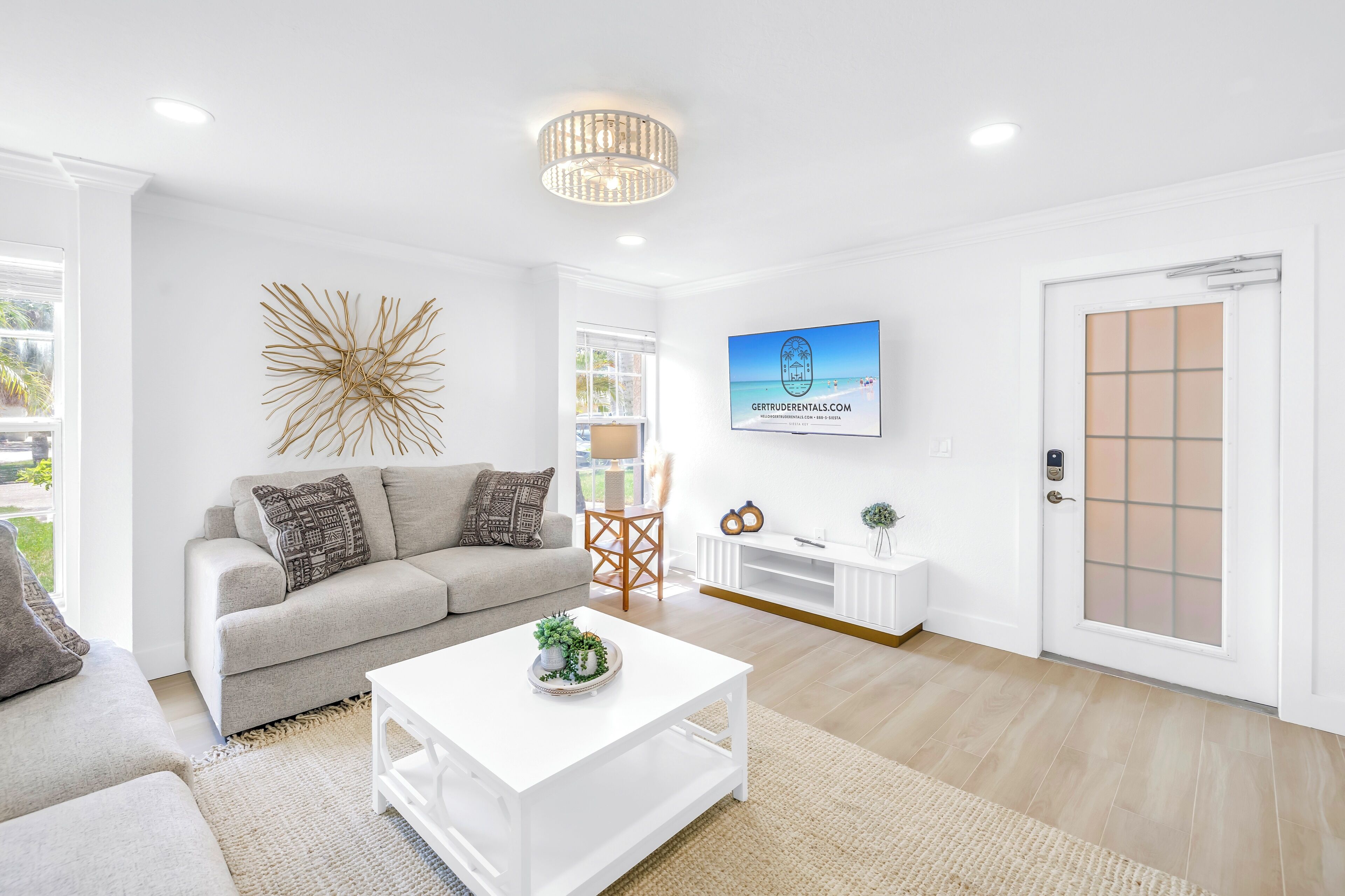 A modern living room with a sofa, coffee table, and a TV mounted on the wall.