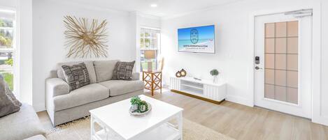 A modern living room with a sofa, coffee table, and a TV mounted on the wall.