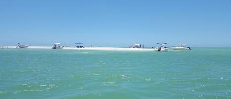A beach with boats, umbrellas, and people.