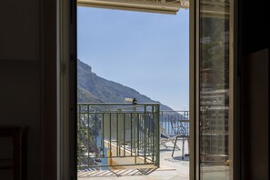 A balcony with a metal gate, a chair, and a table. - Sea Soul Positano (Positano)