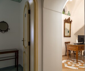 A room with a wooden desk, a chair, a mirror, and a patterned floor. - Sea Soul Positano (Positano)