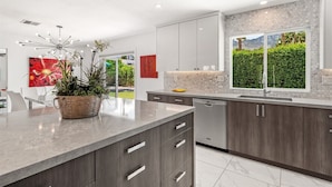 Una cocina moderna con armarios grises, una isla grande y vistas de un jardín a través de una ventana.