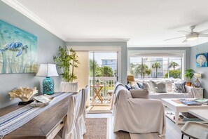A spacious living area with a balcony, a ceiling fan, and a view of the outside. - Island Retreat Walk to Beaches & Harbor (Destin)
