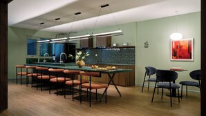 Una cocina moderna con una isla central, taburetes de bar e iluminación colgante.