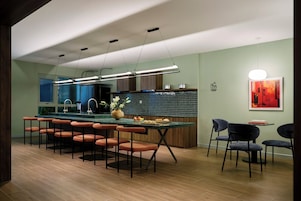 A modern kitchen with a central island, bar stools, and pendant lighting.