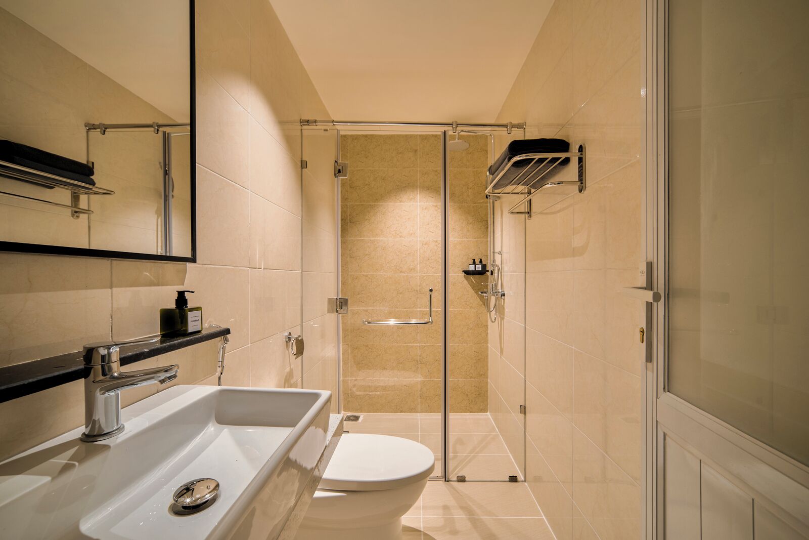 A modern bathroom with a glass-enclosed shower, a white sink, and a toilet.