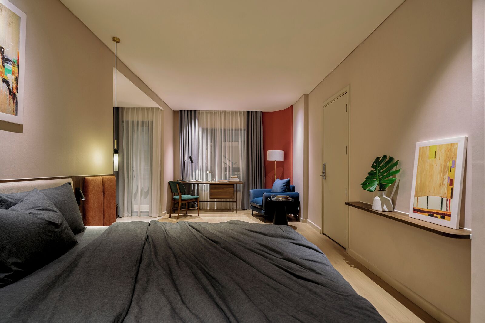 Une chambre d’hôtel moderne, dotée d’un grand lit, d’un bureau, d’une chaise, d’un canapé et d’une petite table.
