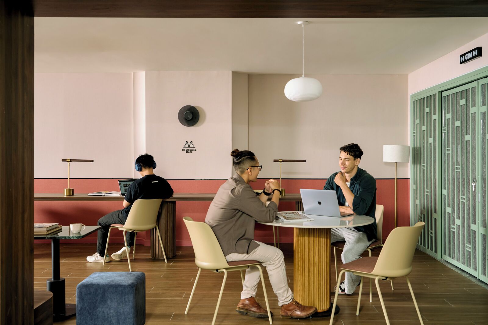 A co-working space with a round table, chairs, a laptop, and a sign indicating a co-working area.