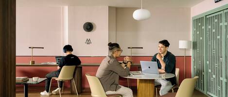 A co-working space with a round table, chairs, a laptop, and a sign indicating a co-working area.