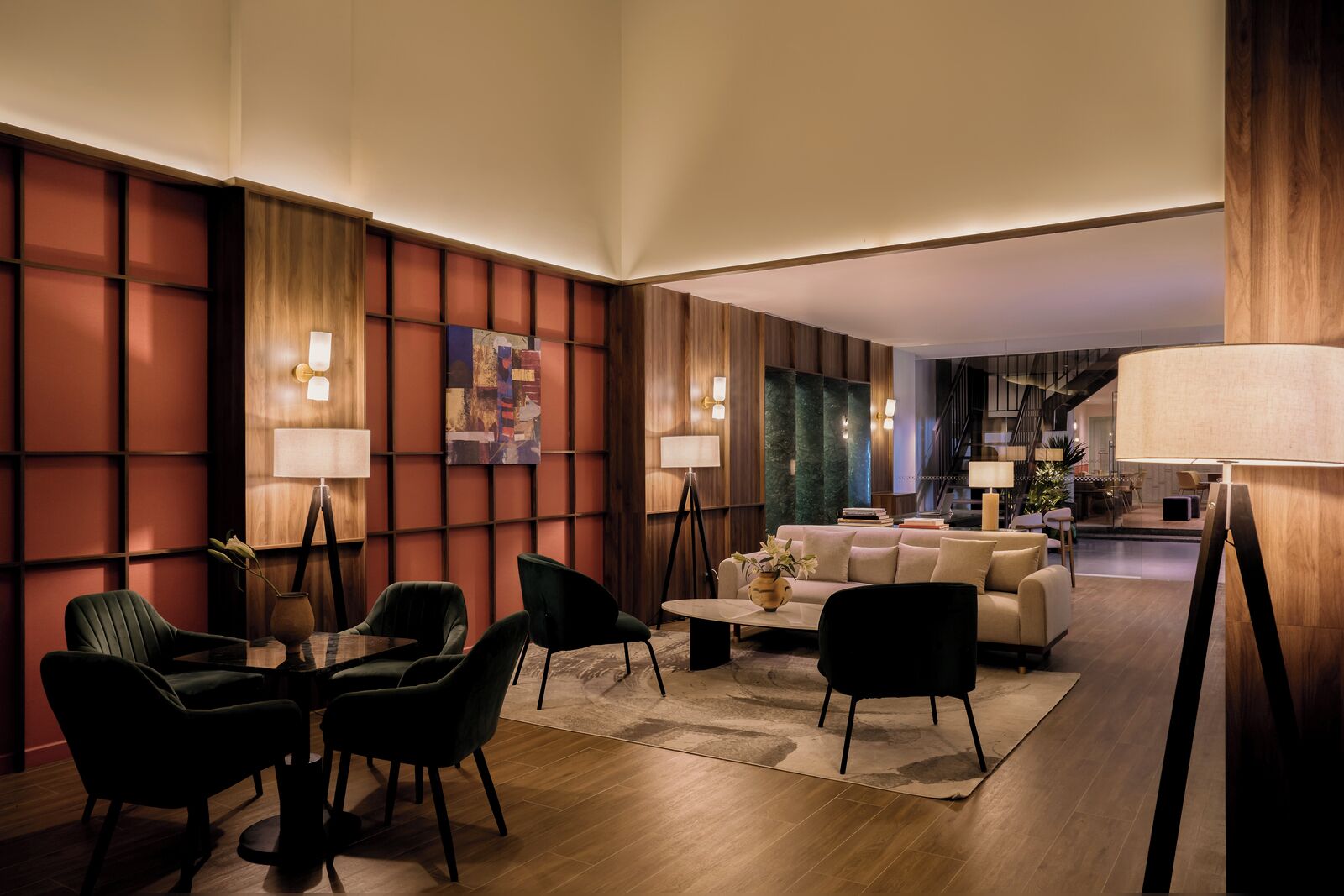 Un salon moderne avec un canapé, des fauteuils et une table basse. Un tableau est accroché au mur et une lampe se trouve sur un pied.