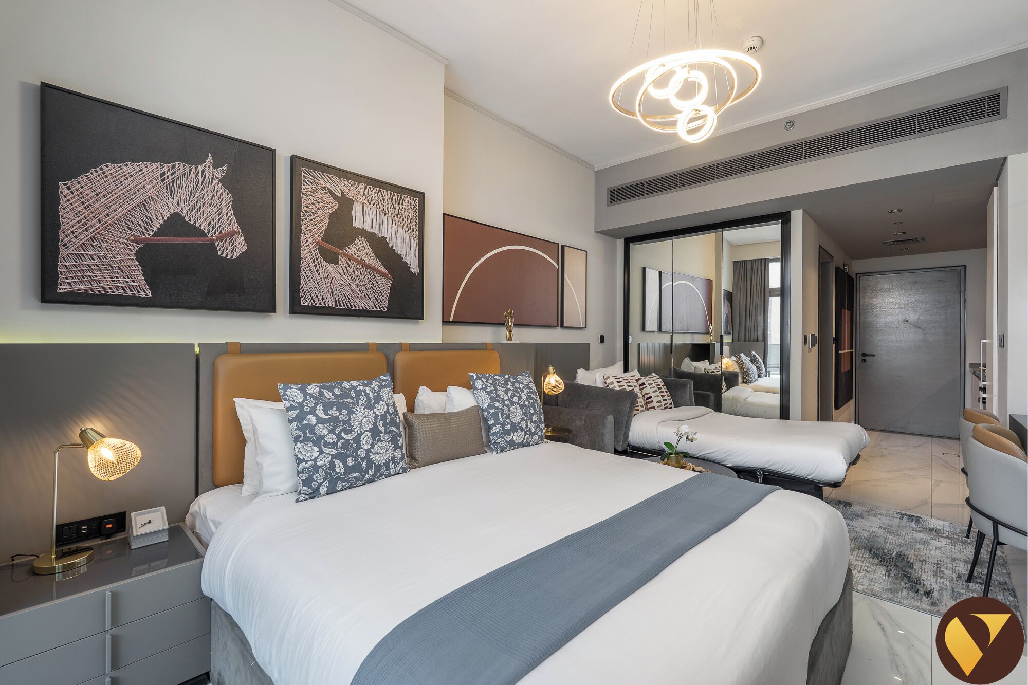 Une chambre d’hôtel moderne avec un grand lit, des tables de chevet, un bureau et un miroir.