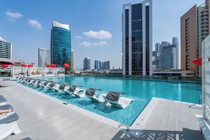 A rooftop pool with lounge chairs and a city skyline in the background. - Vogue| Downtown close to Burj Khalifa | Dubai Mall (Dubai)