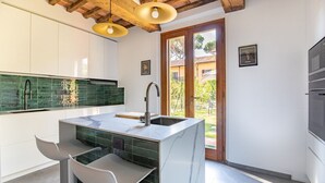A modern kitchen with a marble island, white cabinets, and a green backsplash.