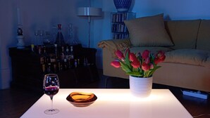 Een moderne woonkamer met een witte salontafel, een vaas met rode bloemen en een wijnglas.