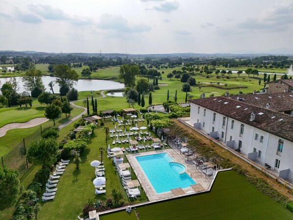 A resort with a swimming pool, lounge chairs, and a golf course in the background.