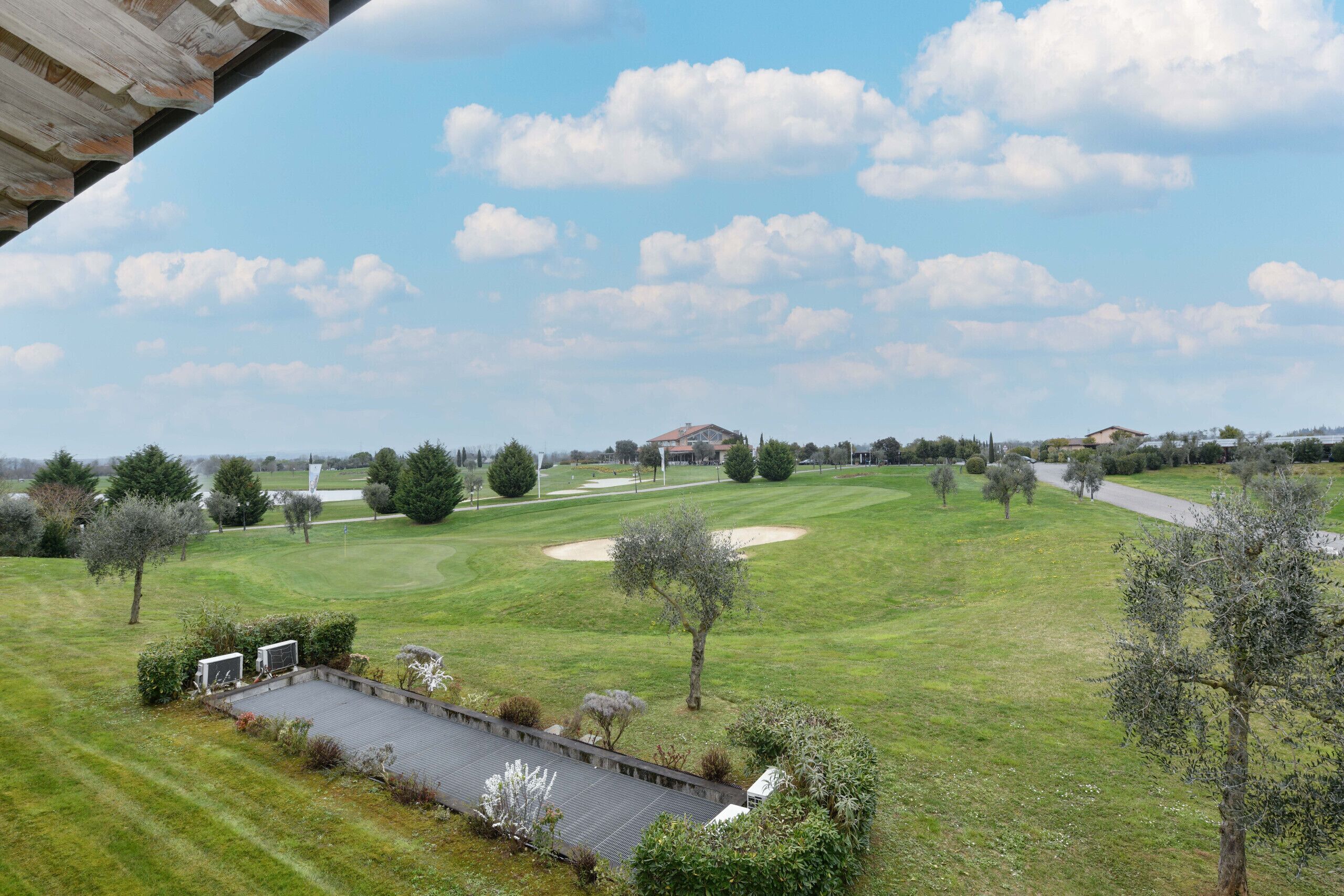 Campo de golf con club house, búnkeres de arena y un sendero para peatones.