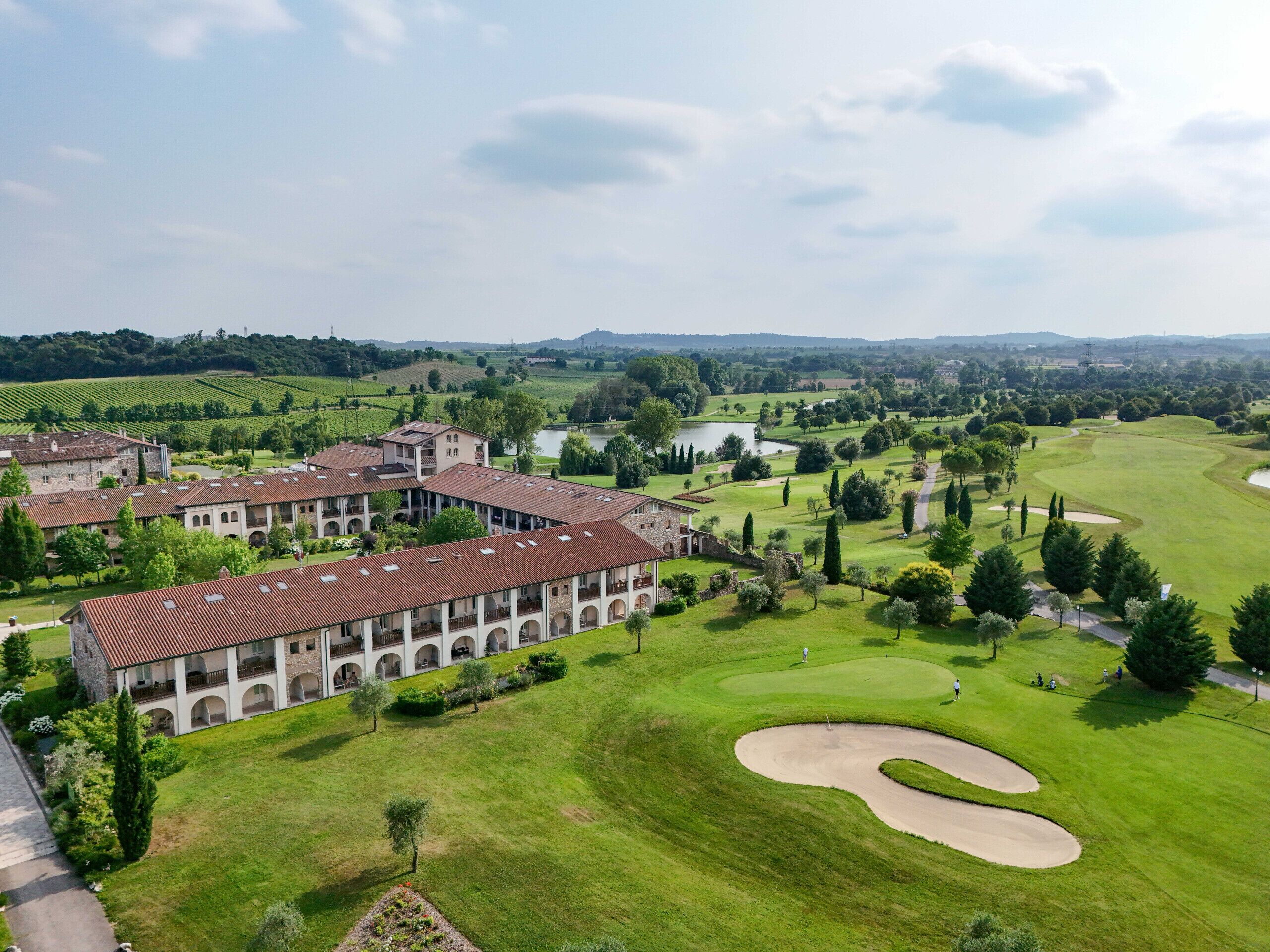 A large building with multiple floors and arched windows, surrounded by well-maintained lawns and a golf course.