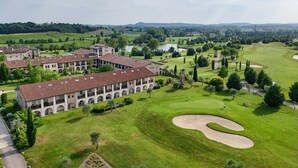 A large building with multiple floors and arched windows, surrounded by well-maintained lawns and a golf course.