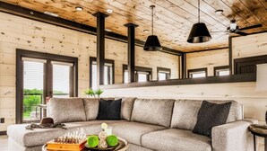 A modern living room with a sectional sofa, a round coffee table, and a fireplace. - Luxury 5BR Getaway | Theater Room | Rooftop Fire Table | Walk to Water Park | Pools | Sleeps 22 (Sevierville)