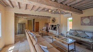 Un amplio salón con techo de madera, chimenea de piedra y un conjunto de sofás.