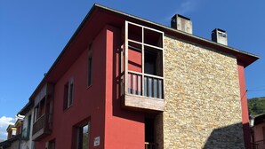 Un edifici amb façana vermella i mur de pedra, amb seients a l'exterior i un rètol que diu "DE MAMA".