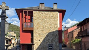 Edifici amb façana de pedra i secció superior vermella, amb terrasses exteriors i un rètol que diu 'DE MAMA'.