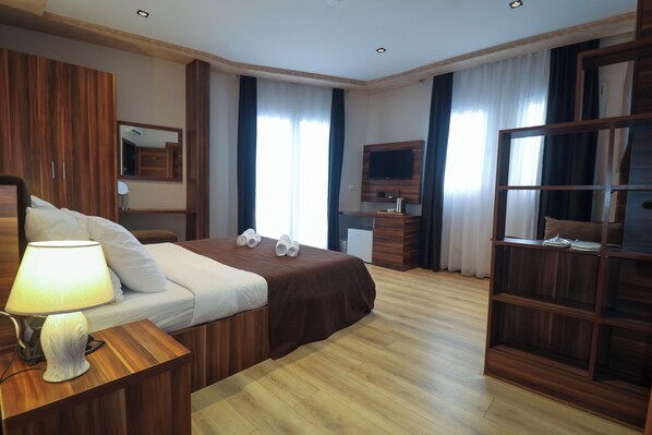 Quarto de hotel com uma cama grande, móveis de madeira, uma televisão e um guarda-roupa.