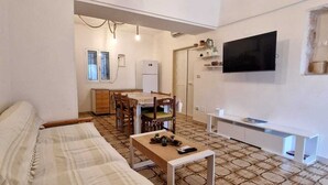 A compact living space with a bed, a dining area, a TV, and a patterned floor.