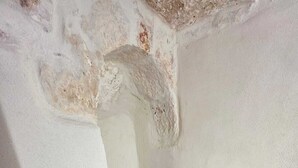 A room with a stone floor, white walls, and a small window.