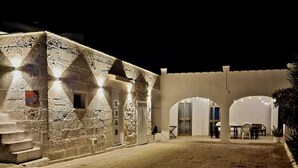 A stone building with arched doorways and a paved courtyard at night.