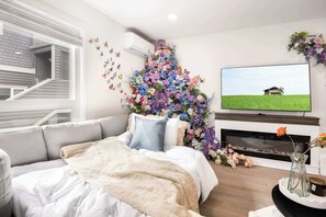 A modern living room with a sofa, a fireplace, and a large TV.