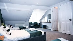 Une chambre moderne avec deux lits, une télévision et une porte donnant sur une autre pièce.
