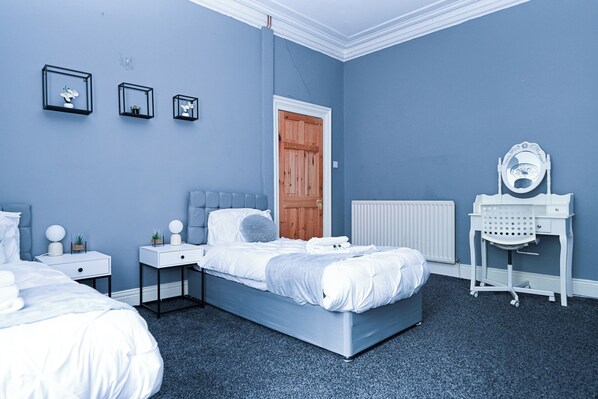 A bedroom with a bed, two bedside tables, a dresser, a mirror, and a radiator.
