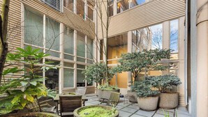 A courtyard with potted plants, a wooden table, and chairs.