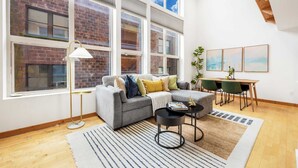 A modern living room with a grey sofa, a round coffee table, and a dining area with a wooden table and chairs.