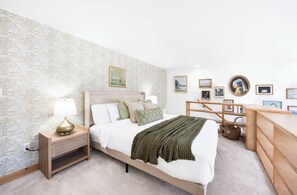 A bedroom with a bed, bedside table, lamp, and wall art. - Historic DT Loft w/ 16ft Ceilings, Garage &97 WS! (Seattle)