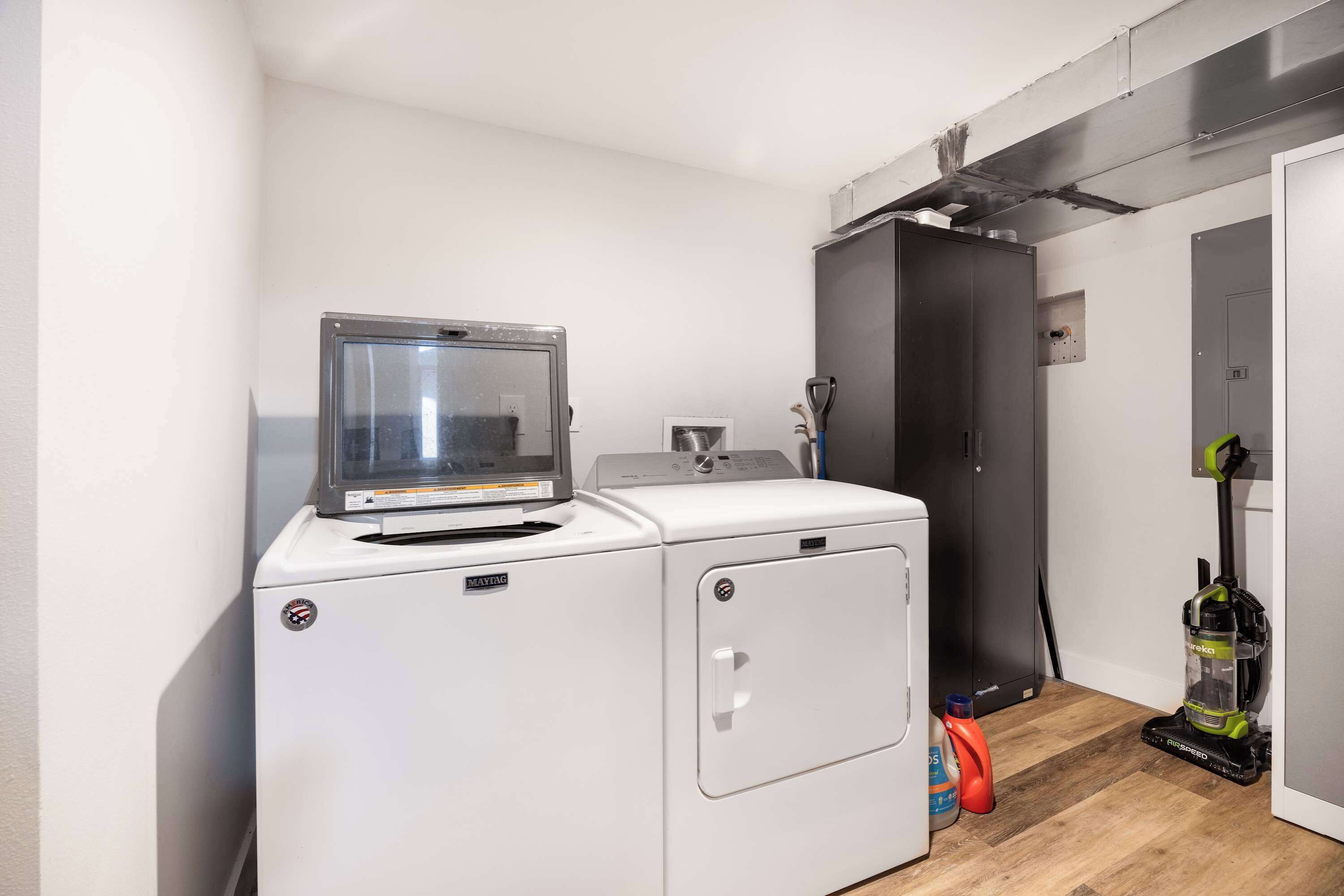 A laundry area with a washing machine, a dryer, and a vacuum cleaner.