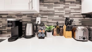 Eine moderne Küche mit Kaffeemaschine, Wasserkocher, Toaster und einer Kapselhalterung.