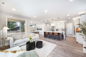 Una cocina moderna con una isla central, taburetes de bar e iluminación colgante.