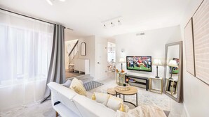 Una sala de estar moderna con sofá, televisión y adornos decorativos.