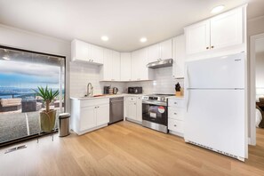 Une cuisine moderne avec des armoires blanches, des appareils en acier inoxydable et une vue sur la ville.