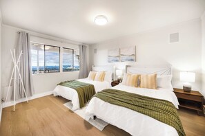 Une chambre d’hôtel avec deux lits, une vue sur la ville et une grande fenêtre avec des rideaux.