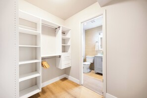 Un dressing accessible sans porte, doté d’étagères ouvertes, d’une tringle et d’un petit meuble à tiroirs.