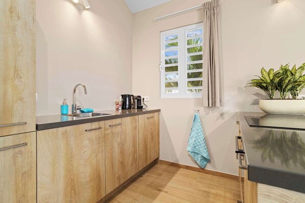Una cocina moderna con armarios de madera, un lavamanos de acero inoxidable y una ventana con persianas.
