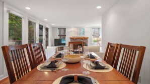 A dining area with a wooden table set for four, surrounded by wooden chairs. - Rare Private Deck, Dog Friendly, Walk to Harbor! (Provincetown)