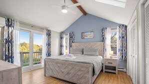 Een slaapkamer met een bed, nachtkastje en uitzicht op het omliggende landschap.